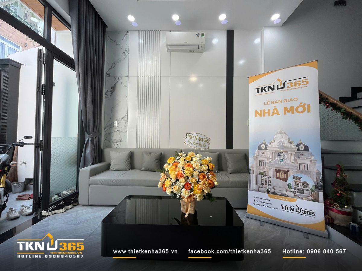 Bố cục phòng khách cân bằng, sofa xám trung tính và bàn kính đen giữ nét hiện đại, trang nhã