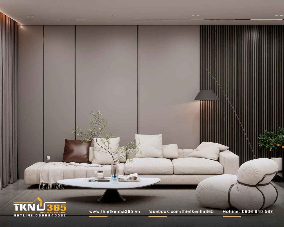 Sofa vải sáng kết hợp ghế lounge bo tròn và bàn trà thấp định hình bố cục trung tâm, giữ nhịp điệu mềm mại giữa các mảng tường phẳng phía sau